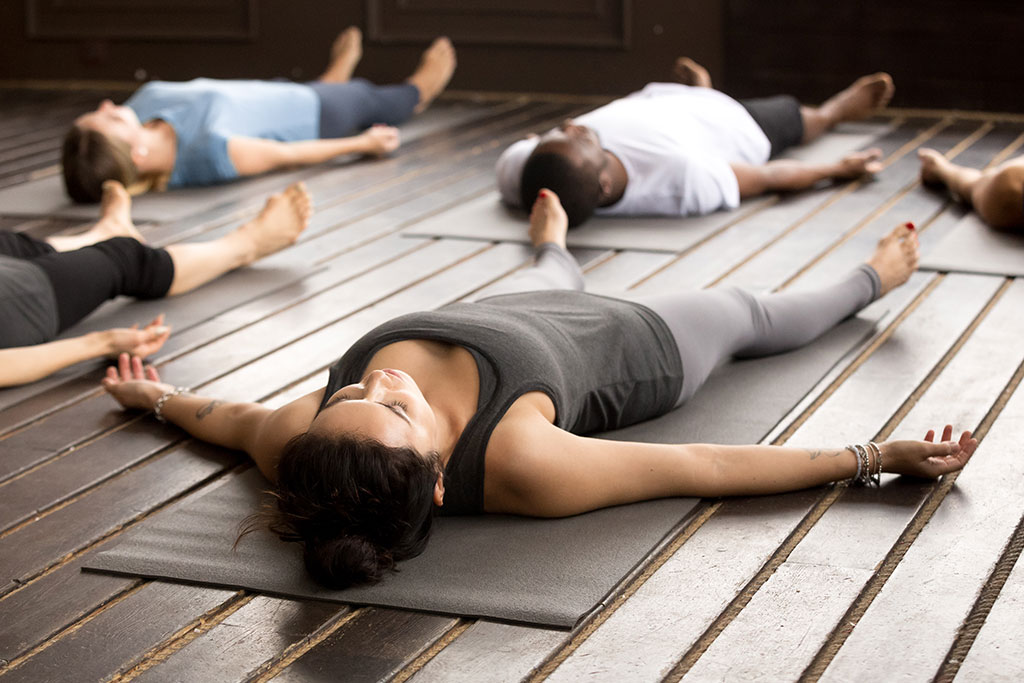 Frau liegt auf einer entspannt auf einer Yogamatte und meditiert